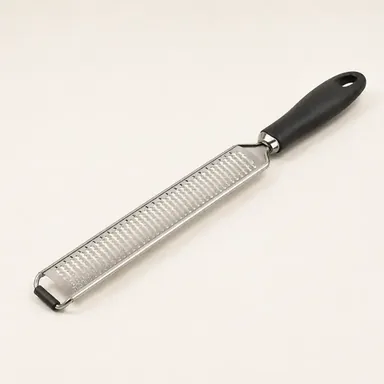 Long fine grater grating hard cheese onto a board