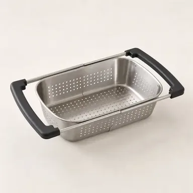 Over-the-sink colander resting across a sink and draining green beans