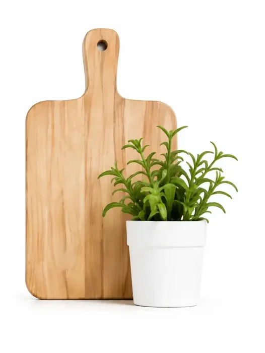 Wooden cutting board standing beside a potted rosemary plant in a white pot