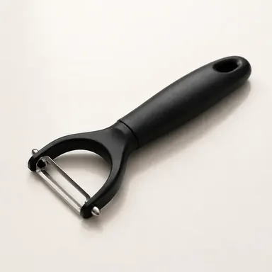 Swivel peeler removing a thin strip of peel from a vegetable